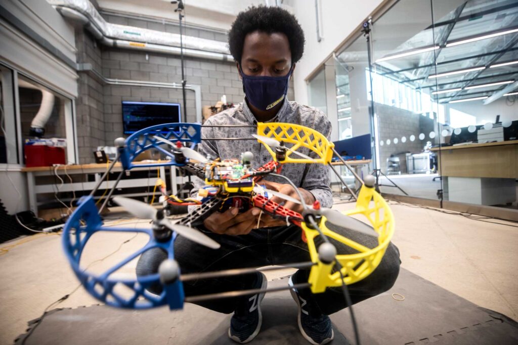 Prince Kuevor, Robotics PhD Student, changes a battery on a drone in the Fly Lab in the U-M Ford Robotics Building. The Fly Lab enables students and researchers to test various aerial vehicles in a three-story space with motion tracking cameras. Image credit: Joseph Xu, U-M Engineering, Communications and Marketing