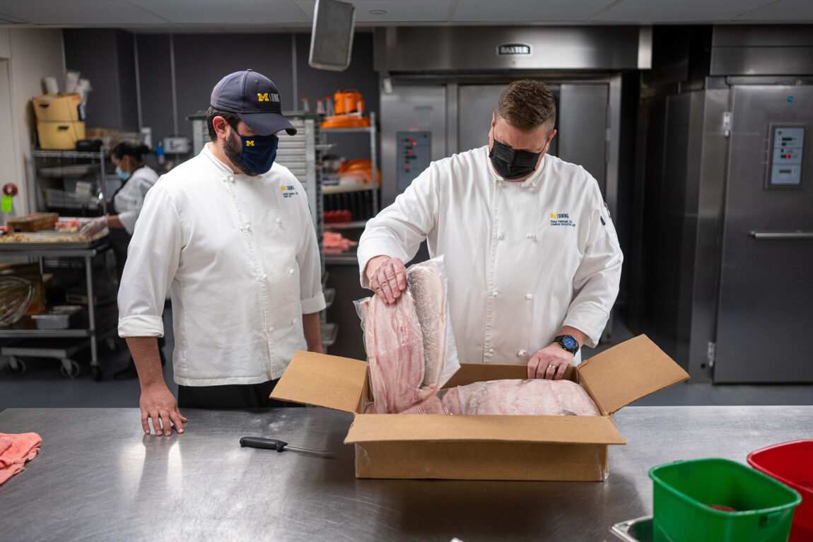 Executive Chef Frank Turchan unpacks a box of fish fillets as David Burnell, sous chef at South Quad, looks on. (Eric Bronson, Michigan Photography)