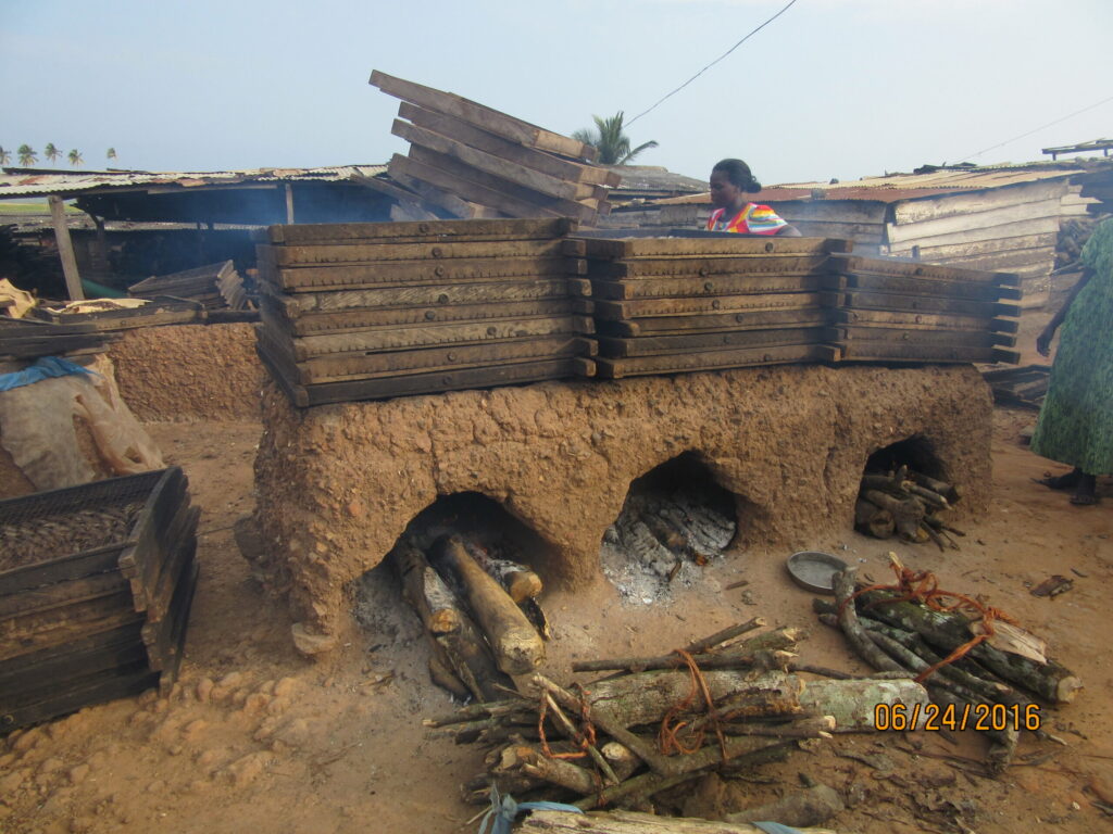 Firewood is loaded into the rudimentary mud ovens, and trays of fish are stacked on top for smoking, which is done to preserve the fish. Image credit: Pam Jagger