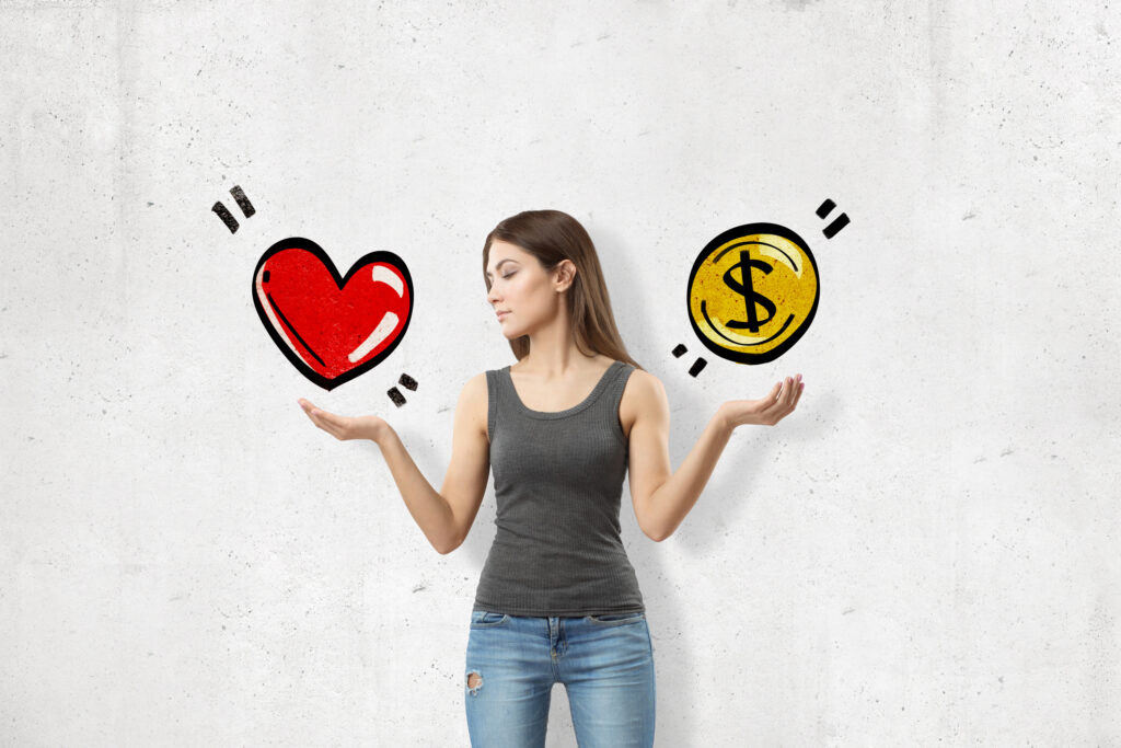 A young woman comparing a cartoon heart and a cartoon coin. Image credit: iStock