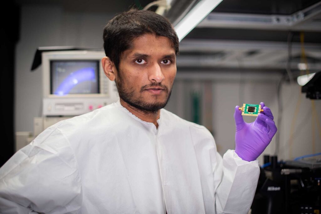 Kanak Datta holds the chip that can transport excitons on acoustic waves. The new technology paves the way for transporting energy efficiently with excitons. Image credit: Silvia Cardarelli
