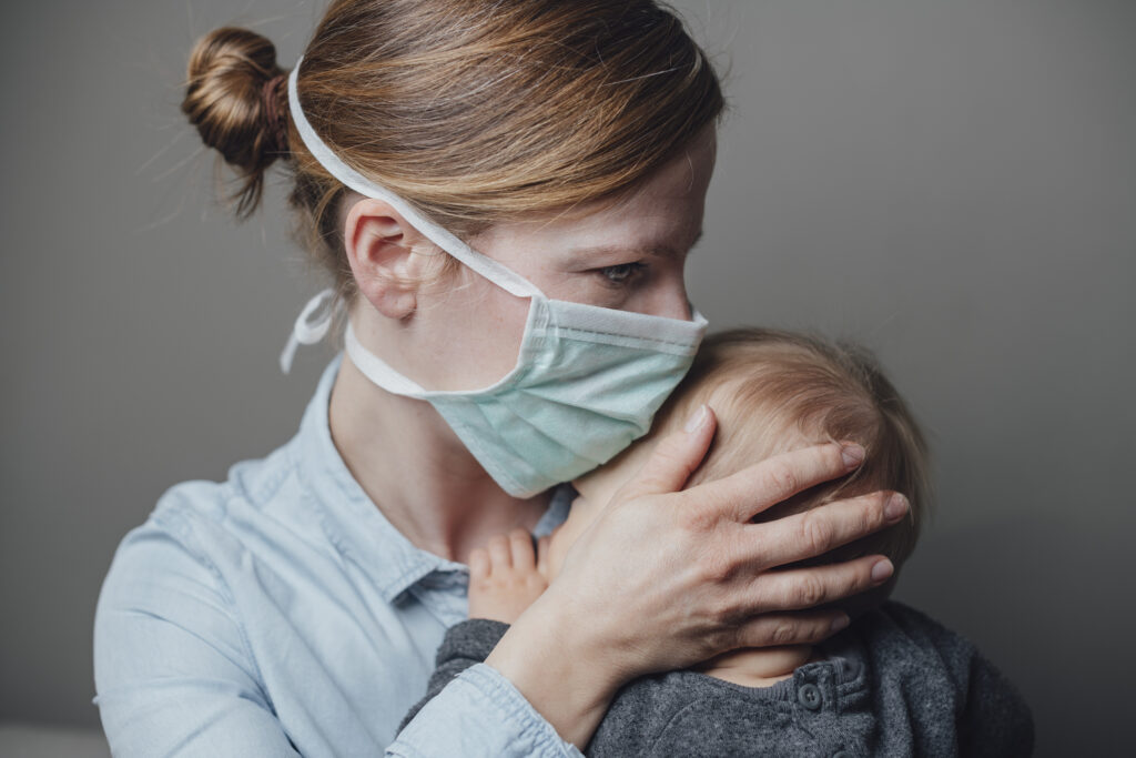 A masked woman with a child. Image credit: iStock
