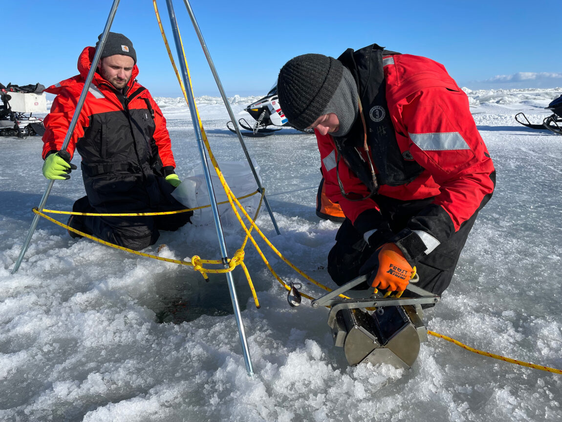 Andrew Camilleri, left, and Hayden Henderson, both from U-M's Cooperative Institute for Great Lakes Research, prepare to deploy a jawed, stainless steel device called a Petite Ponar grab sampler. It was used to collect bottom sediments and a few quagga mussels during the Feb. 15 Saginaw Bay trip. (Michigan News photo.)