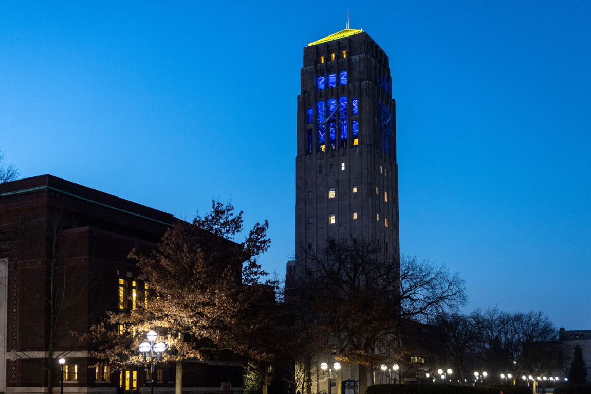 Photo of Burton Memorial Tower in blue and gold light