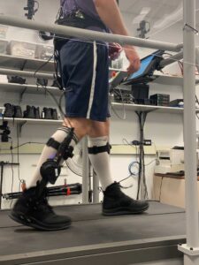 A study participant walks on a treadmill with a tablet that allows them to change the timing and torque of the exoskeleton they are wearing. Image credit: Kim Ingraham