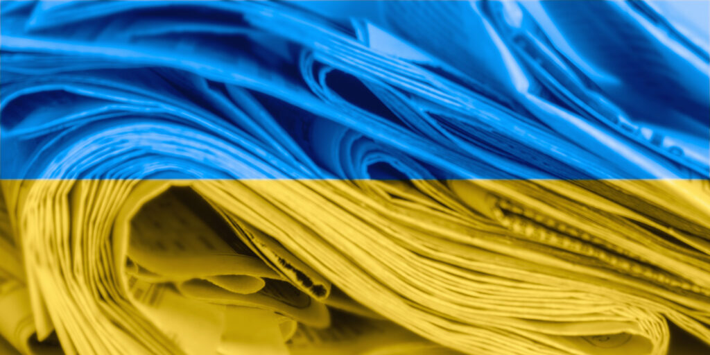 News media concept: Abstract, blurred image of newspapers on the background of the flag of Ukraine. Image credit: iStock