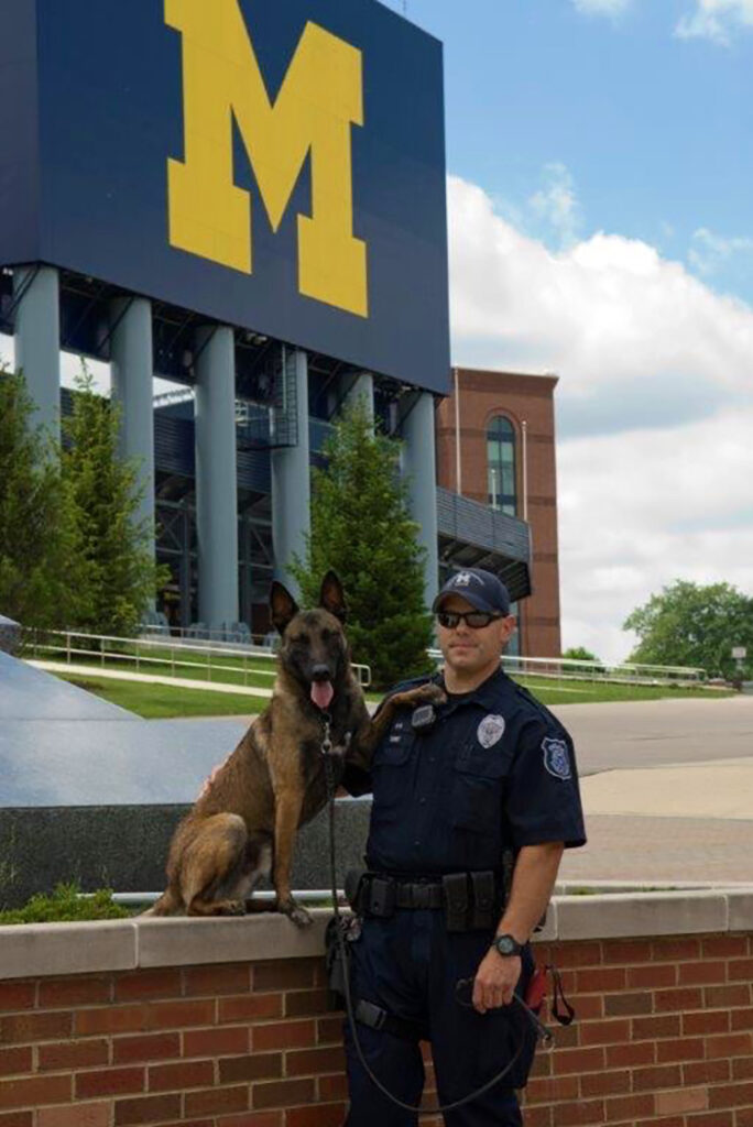 Officer Joseph Dunny and his previous K-9 partner, Tank, pose outside Michigan Stadium, where the pair patrolled every home football game. (Photo courtesy of Joseph Dunny)