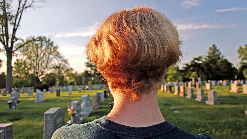I young man looks out over a cemetary. Image credit: iStock