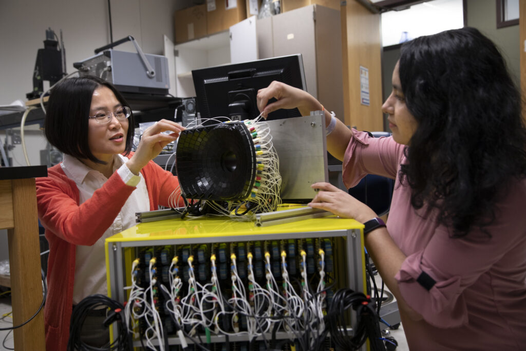 Zhen Xu,Professor of Biomedical Engineering at the University of Michigan (left) and Tejaswi Worlikar, Biomedical Engineering PhD student discuss the 700kHz, 260-element histotripsy ultrasound array transducer they use in Prof. Xu’s lab. Image credit: Marcin Szczepanski, Michigan Engineering
