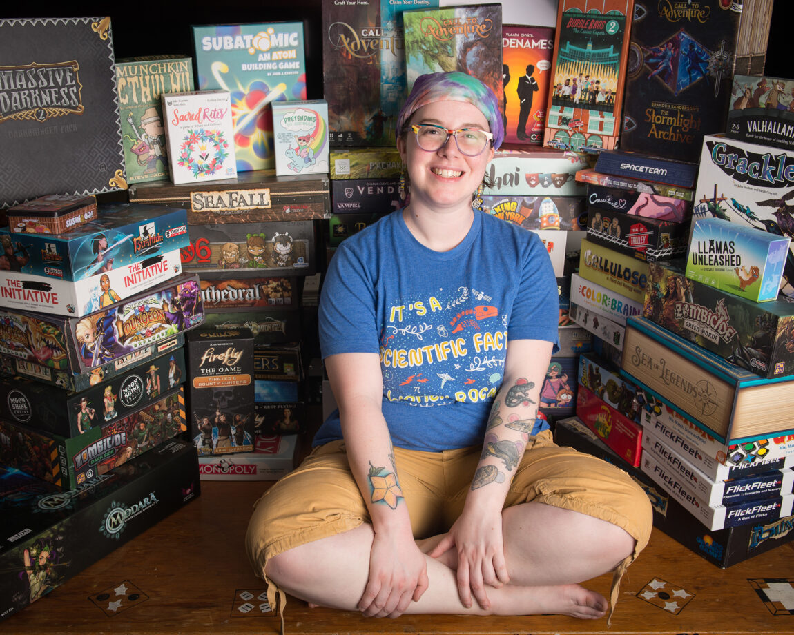Christine Kitchens, research technician with the Cooperative Institute for Great Lakes Research, sits among the scores of board games she and her partners have accumulated over the years. (Photo by Rad DeLong)