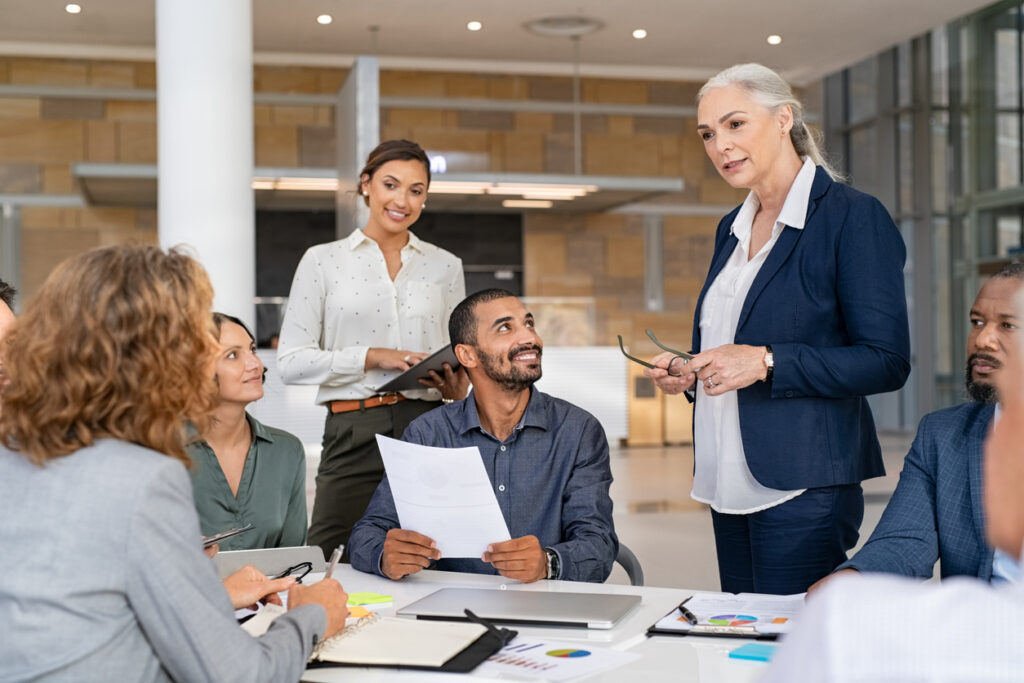 A woman standing while conducting a meeting. Image credit: iStock