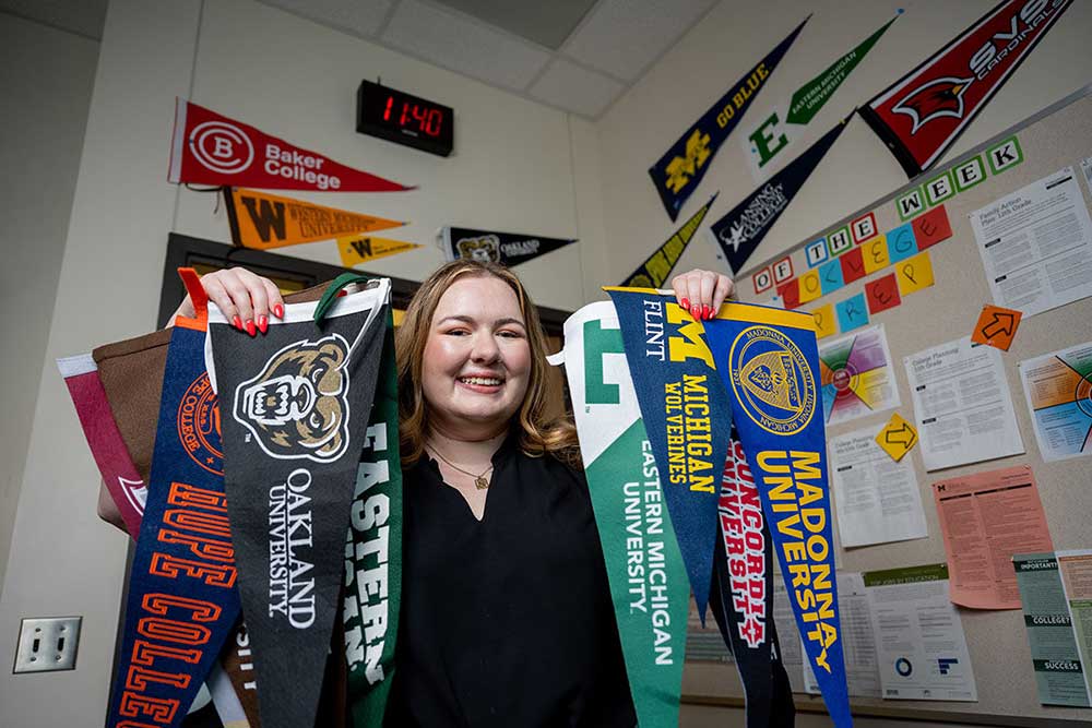 Battle Creek Central High’s Charlotte Pierce with banners of the colleges students will attend. Image credit: Eric Bronson, Michigan Photography