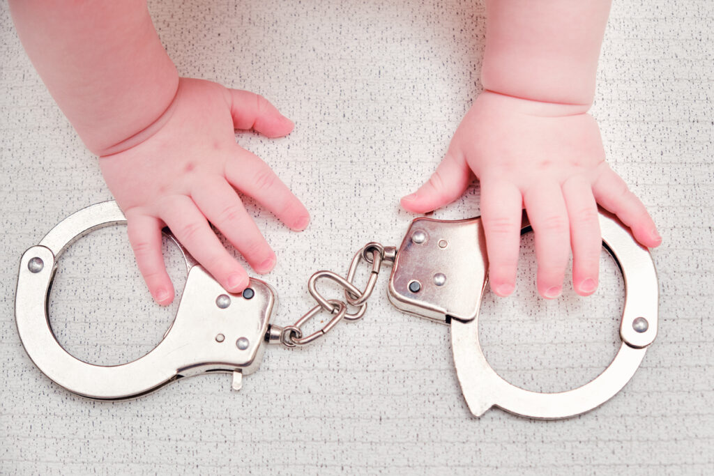 Baby hand and handcuffs, close-up. Image credit: iStock