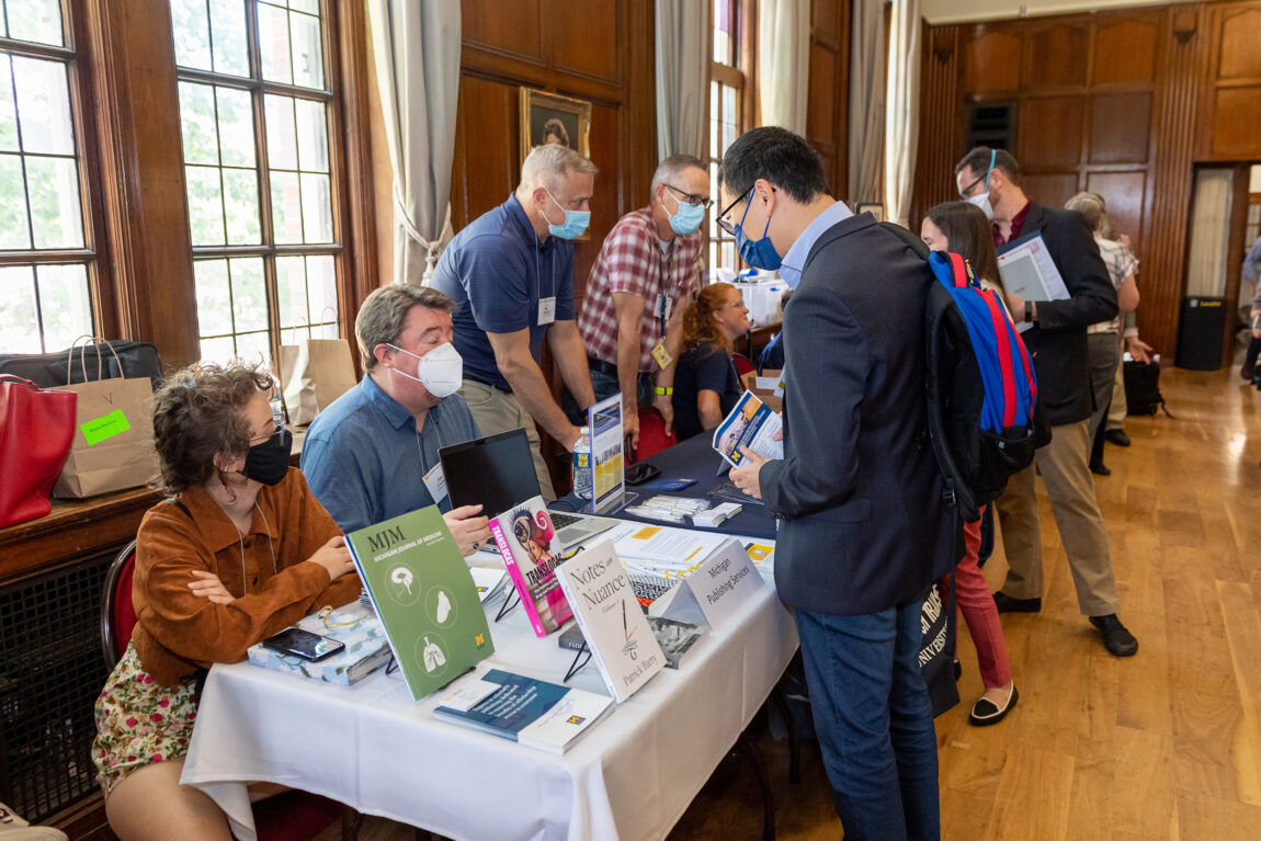 A participant at the 2022 New Faculty Orientation speaks with Marisa Mercurio and Jake Carlson of Michigan Publishing Services during the resource fair at the Aug. 24 event. (Daryl Marshke, Michigan Photography)