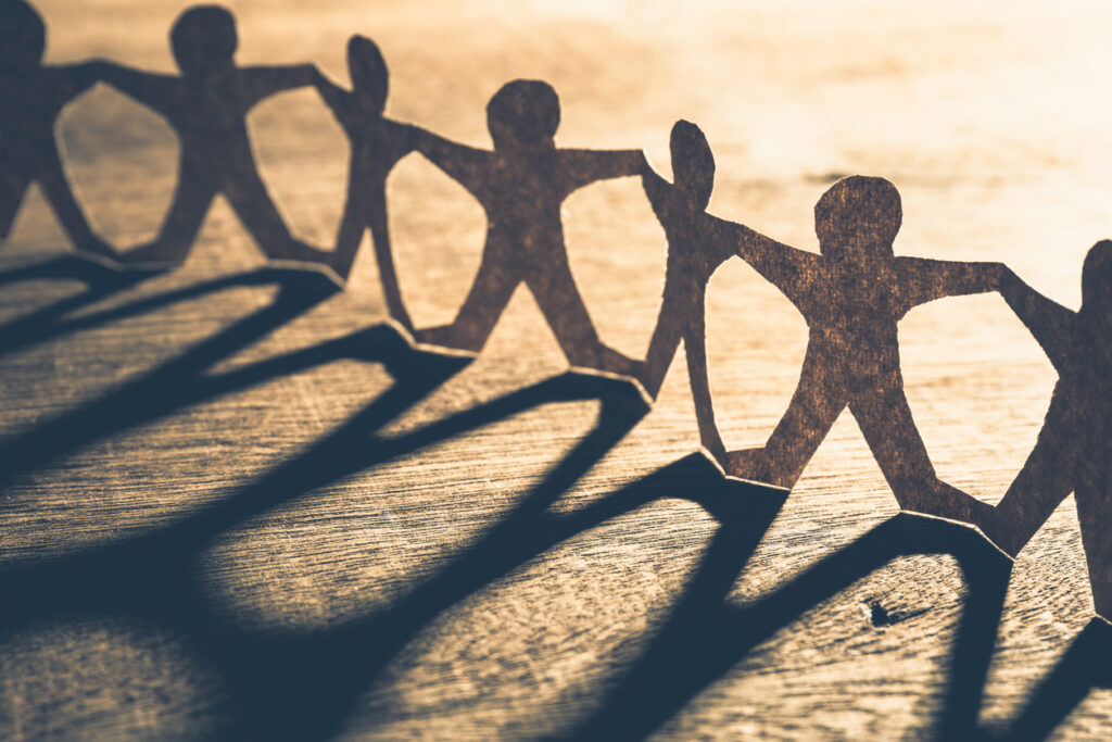 Human chain paper with light and shadow on wood table. Image credit: iStock