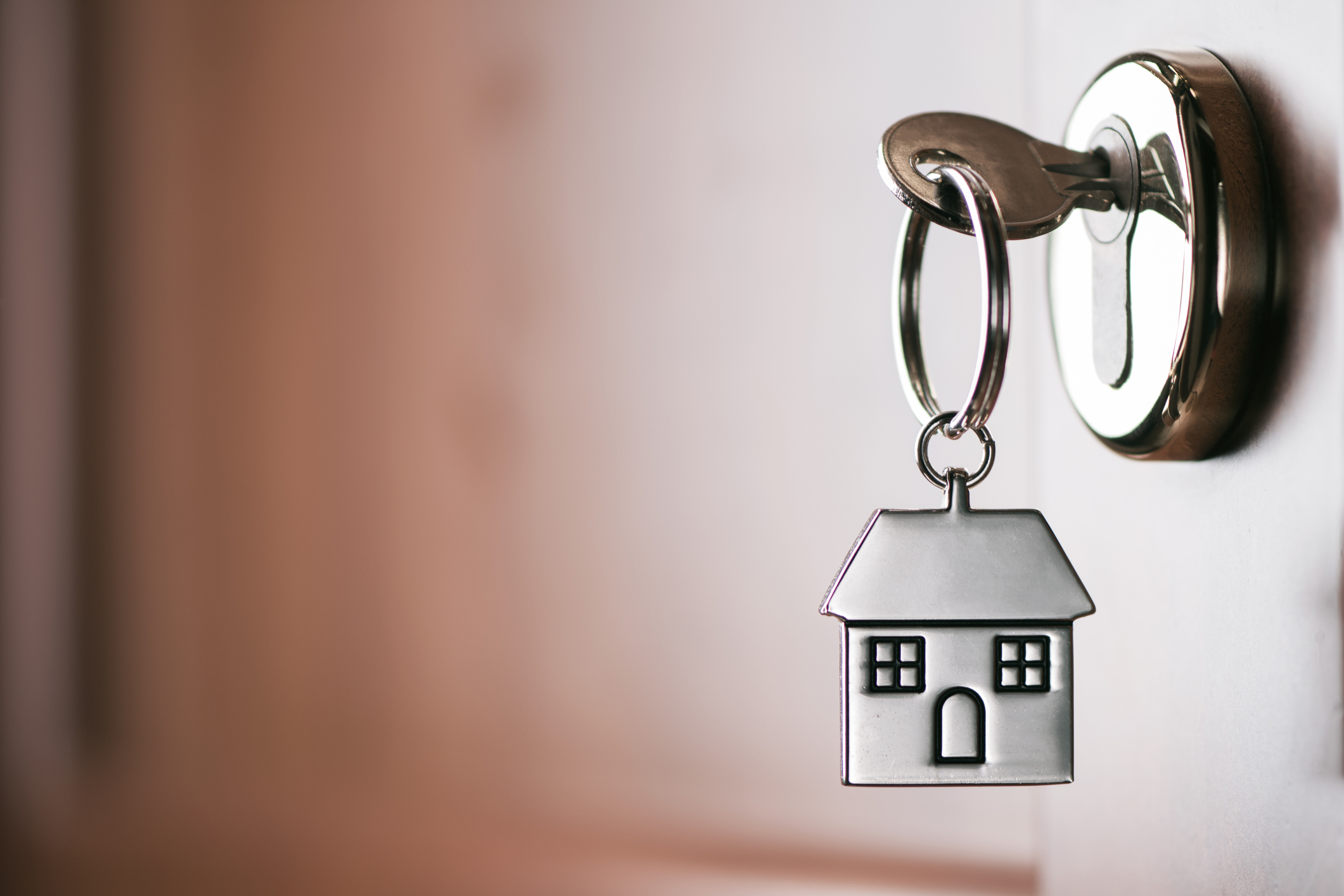 House key on a house shaped silver keyring in the lock of a door. Image credit: FabioBalbi, iStock