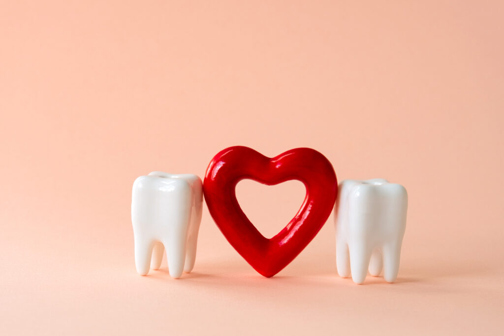 Oral care concept image: two teeth and red heart on a pastel background. Image credit: iStock