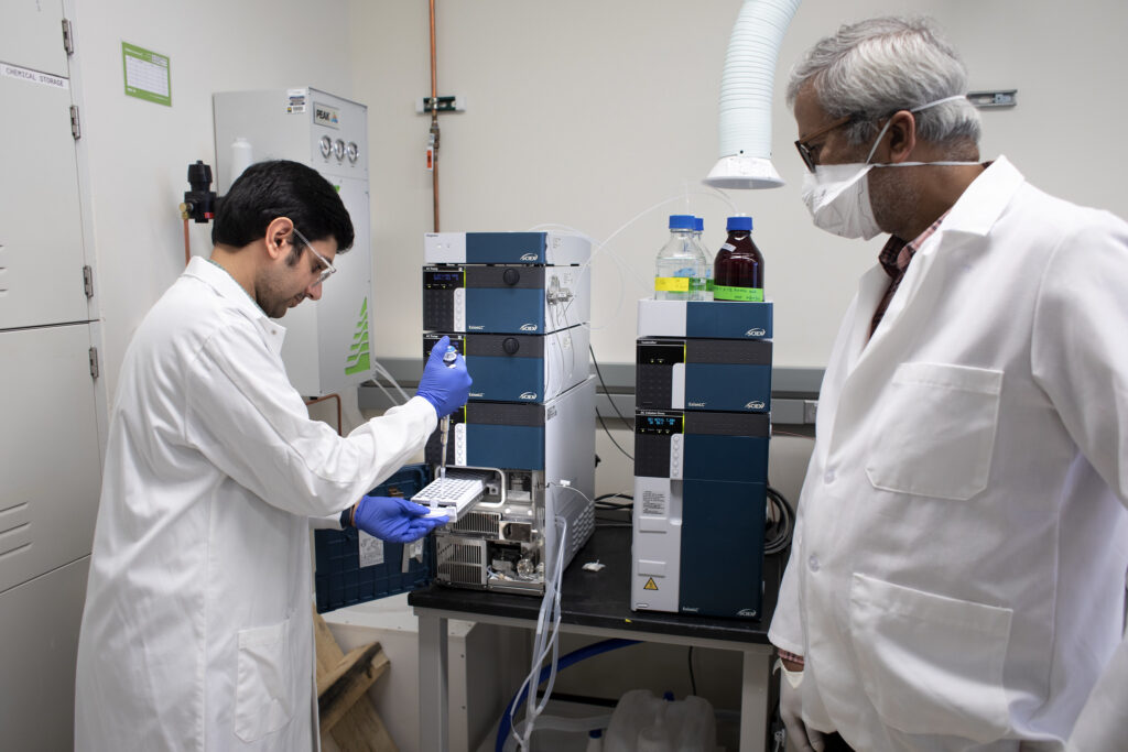Abhinav Achreja, PhD, Research Fellow at the University of Michigan Biomedical Engineering and Deepak Nagrath, Ph.D. Associate Professor of Biomedical Engineering work on ovarian cancer cell research in the bio-engineering lab at the North Campus Research Center (NCRC). Liquid Chromatography Mass Spectrometer (behind them) is one of the main tools they use in their research. Image credit: Marcin Szczepanski, Michigan Engineering