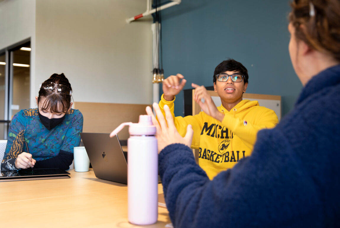 From left, students Martha Ainsworth, Avinjoy Das and Jessica Kennedy discuss an informational sign they designed for a mechanism to secure wheelchairs on a bus. (Photo by Marcin Szczepanski, College of Engineering)