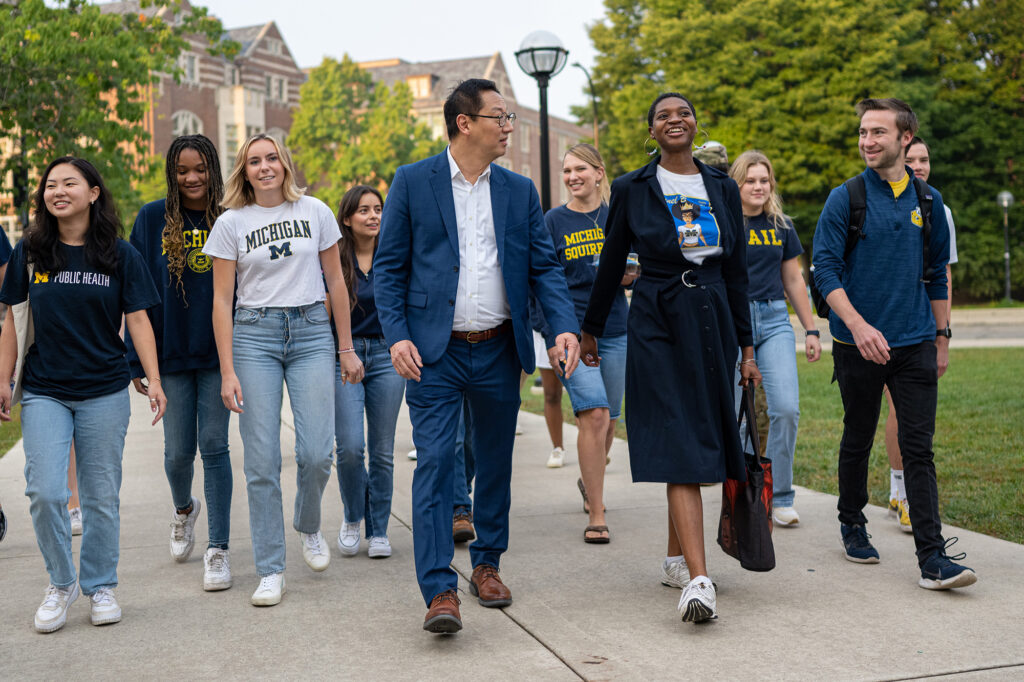 Photo of Santa J. Ono walking and talking with students.