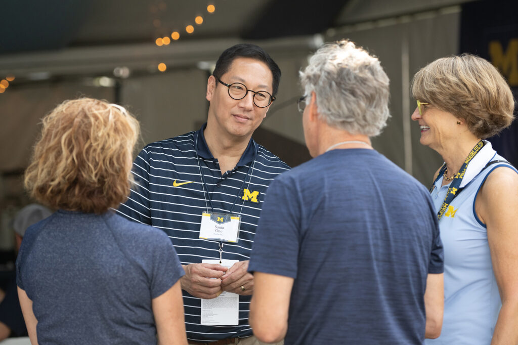 Photo of Santa J. Ono talking with people at a tailgate party