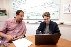 Mackillo Kira, professor of Electrical Engineering and Computer Science, and Markus Borsch, PhD student in electrical and computer engineering, work together in Kira’s office going over some of the fundamental light emission properties for semiconductors in the Engineering Research Building on the North Campus of the University of Michigan in Ann Arbor on Wednesday, August 17, 2022. Image credit: Brenda Ahearn/University of Michigan, College of Engineering, Communications and Marketing