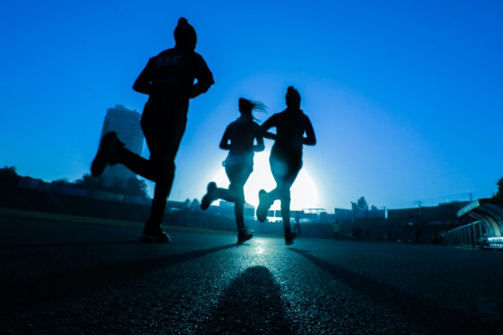 Three people running at dusk. Image credit: Fitsum Admasu via Unsplash