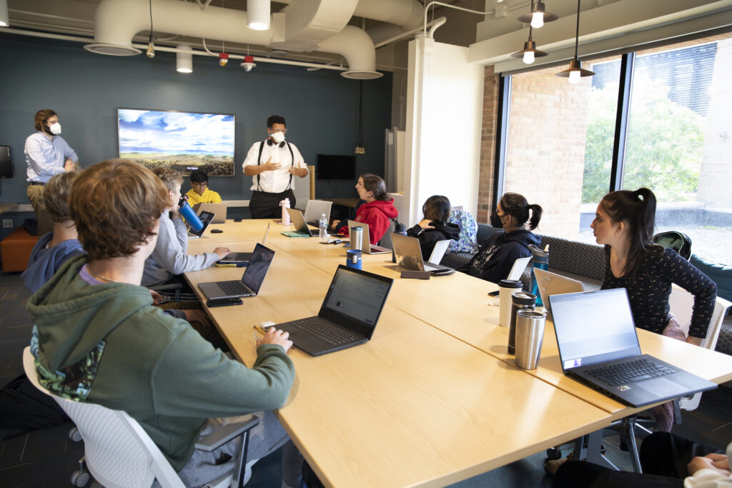 Jesse Austin-Breneman, Assistant Professor at the Department of Mechanical Engineering at U-M, speaks to his students at the ENGIN 100 class about designs for a mechanism to secure wheelchairs on a bus. Image credit: Marcin Szczepanski, Michigan Engineering