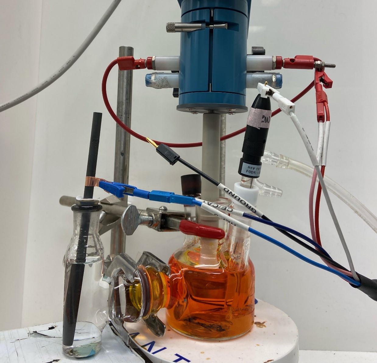The experimental setup. The cerium with four missing electrons in sulfuric acid leads to the orange color of the solution. Three electrodes measure the rate of the electron transfer that moves cerium between the two states. Image credit: Cailin Buchanan, Singh Lab