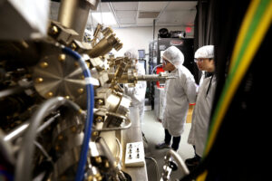 Peng Zhou, right, and Yuyang Pan, first year PhD student, observe the machine in which the semiconductor nanowires are grown. Image credit: Brenda Ahearn/Michigan Engineering, Communications and Marketing