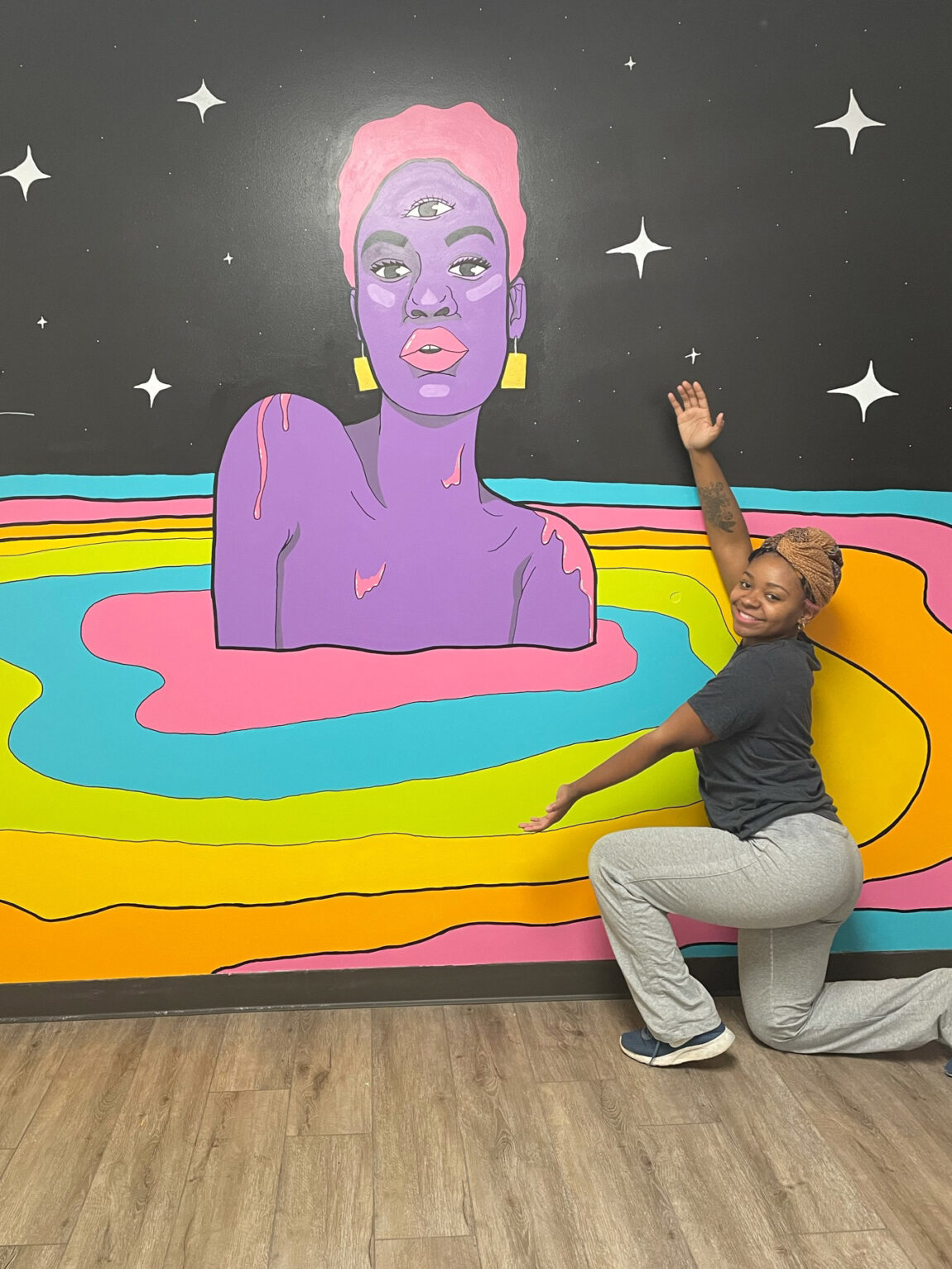 DaJaniere Rice, multimedia graphic designer for LSA Advancement, poses next to a mural she painted for a venue space in Southfield. (Photo courtesy of Jewelle Baggett)