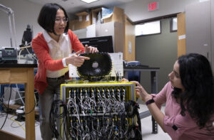 Zhen Xu,Professor of Biomedical Engineering at the University of Michigan (left) and Tejaswi Worlikar, Biomedical Engineering PhD student discuss the 700kHz, 260-element histotripsy ultrasound array transducer they use in Prof. Xu’s lab. Image credit: Marcin Szczepanski/Lead Multimedia Storyteller, Michigan Engineering