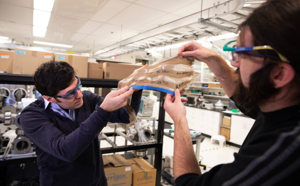 Max Shtein, professor of materials science and engineering in the College of Engineering, and Brian Iezzi analyze the fabric with photonic fibers woven into it. (Photo by Marcin Szczepanski, College of Engineering)