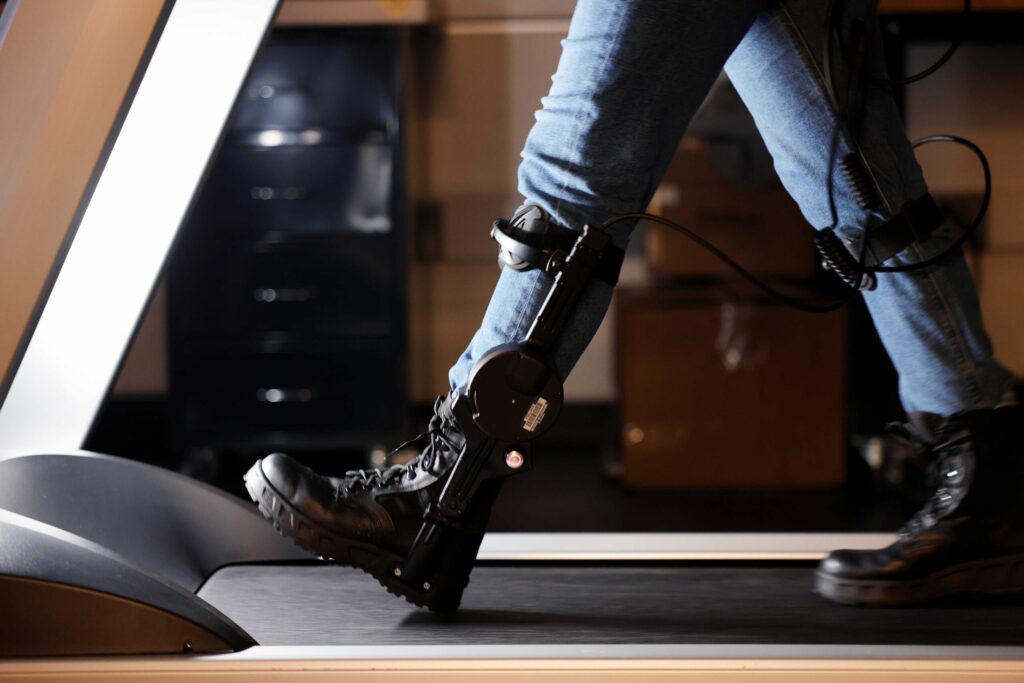 Jacqueline Hannan, a PhD student in industrial and operations engineering, demonstrates walking with an ankle exoskeleton in Stirling's lab. Photo credit: Brenda Ahearn, University of Michigan Engineering