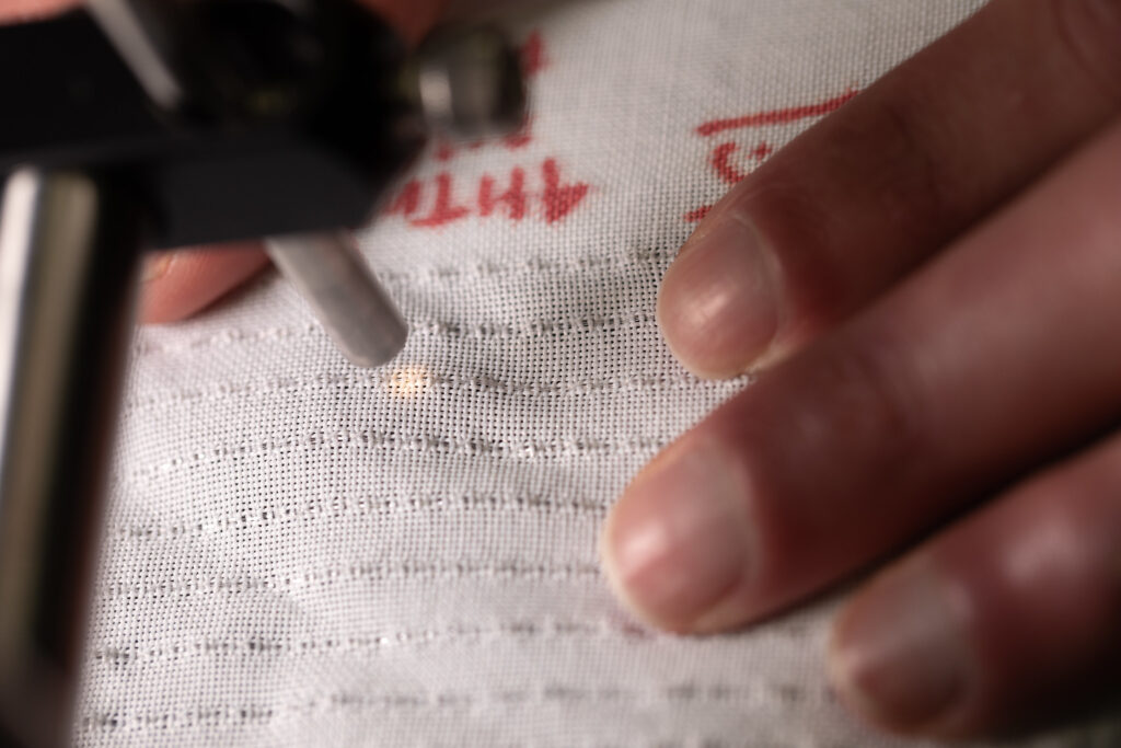 Brian Iezzi scans and measures the photonic fibers in the fabric he developed. Image credit: Marcin Szczepanski/Lead Multimedia Storyteller, University of Michigan College of Engineering