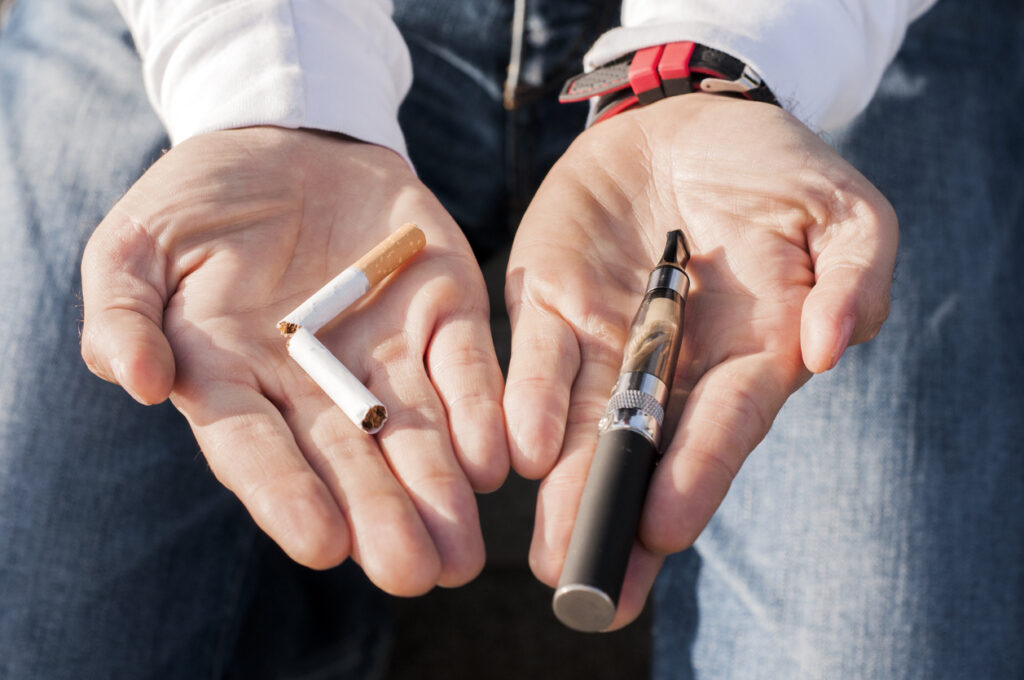 A broken cigarette in one and hand a vape pen in the other. Image credit: iStock