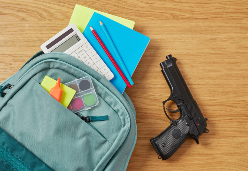 Backpack, school supplies and gun on desk. Image credit: iStock