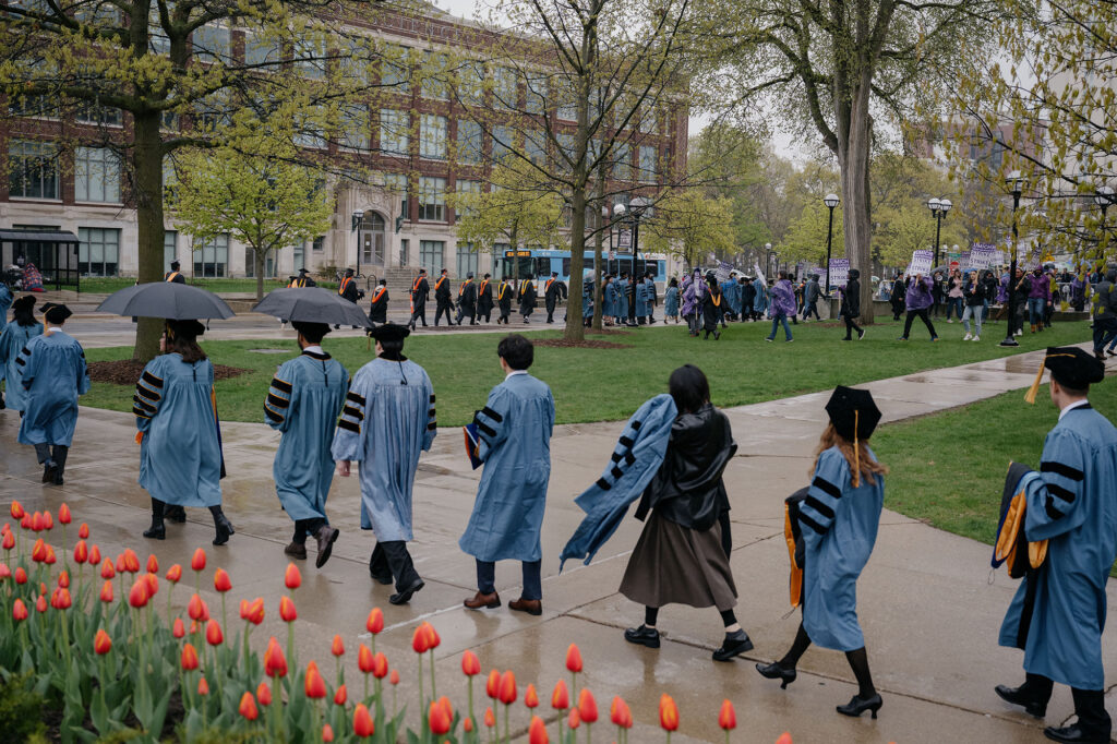 Photo of doctoral candidates in a procession from the Rackham Building to Hill Auditorium.