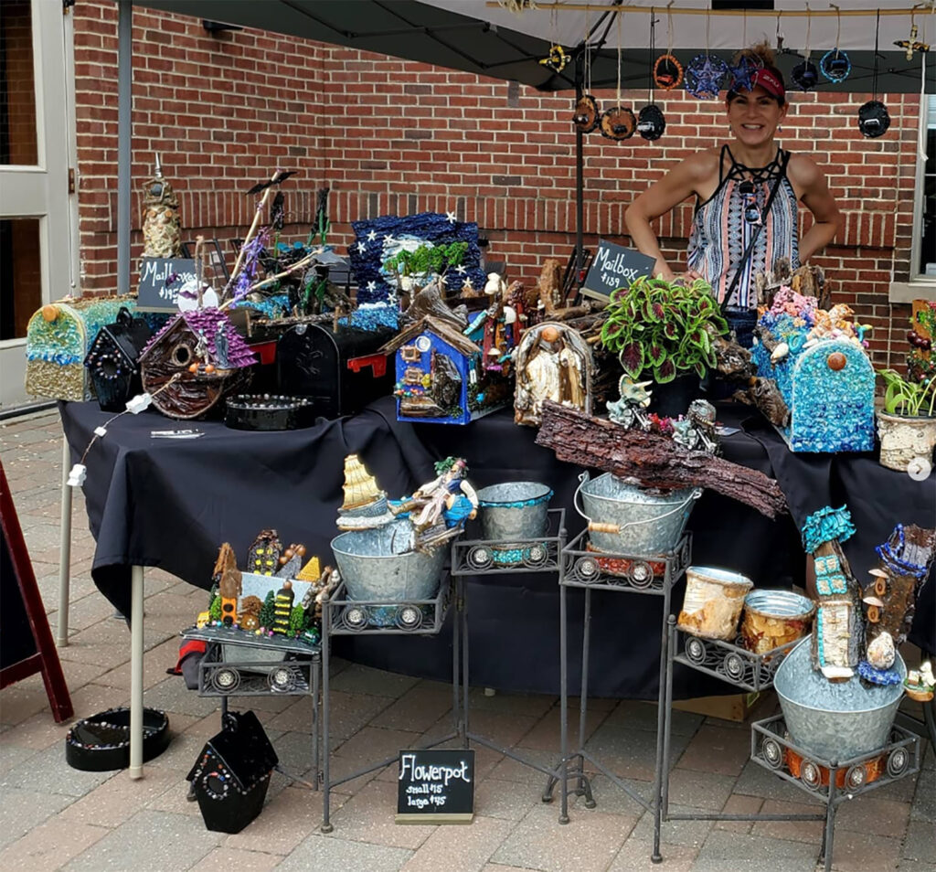 Tamara Havermahl, a research communicator with the Department of Cell & Developmental Biology in Michigan Medicine, stands at the Brighton Farmers Market with several of the mailboxes, birdhouses and flowerpots she has created over the years. (Photo by Marion Moritz)