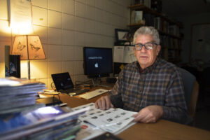 Ricky Rood at his desk, with cinderblock walls and lamp.