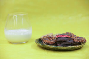 Girl scout cookies on a plate with milk and a yellow background.