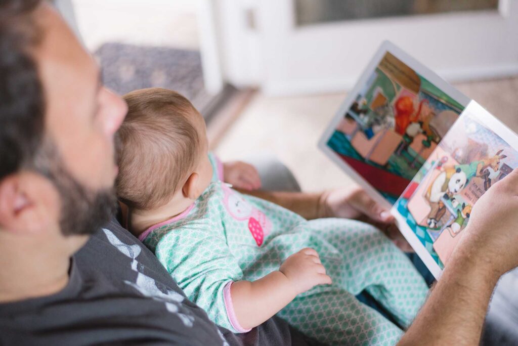 Man reading children's book to a baby. Image credit: Picsea, Unsplash.com