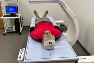 Man in a red shirt lays on a gurney for body scan.