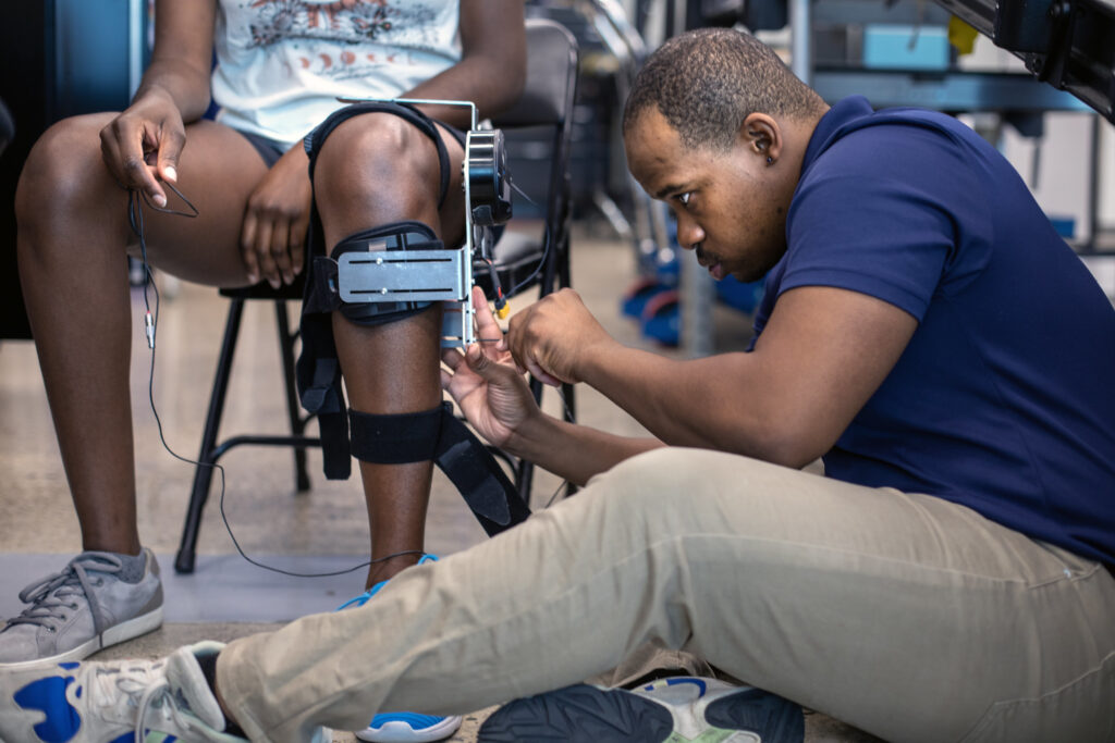 Yves Nazon, PhD student in Professor Elliott Rouse's Neurobionics Lab, works with a research subject Therese Nkeng to measure mechanical properties of the knee joint, such as torque and displacement, as a research subject encounters unexpected forces while walking. Image credit: Marcin Szczepanski, Michigan Engineering