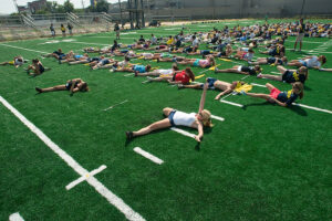 Members of the MMB flag corps lay on the green turf at Elbel Field to stretch before practice.