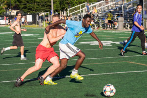 Two soccer opponents compete to control the ball. Action shot.