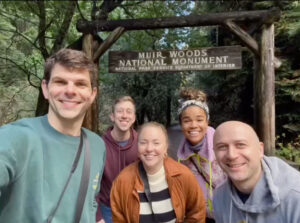 Beetlejuice cast members, a cluster of five people, are pictured under a sign that reads Muir Woods National Monument.