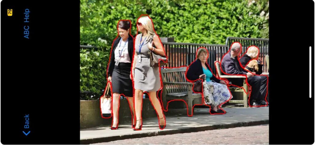 The screenshot shows two women in business dress in the foreground of the photo, and two park benches in the background. One bench has an older woman sitting on it, facing the camera, and the other has two older men who are looking away. ImageExplorer identifies all these in red outline. The wall of greenery, fence, sidewalk and street are not outlined. Image credit: Human-AI Lab