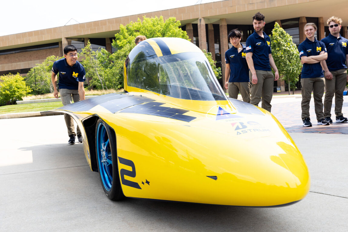 Photo of Terry Li, lead vehicle engineer for the 2023 Michigan Solar Car Team, pushes Astrum into position.