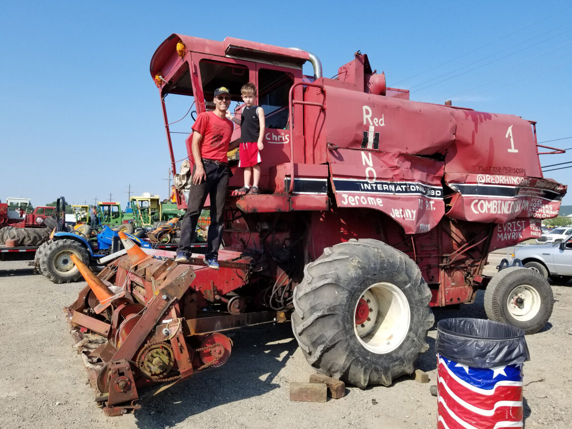 Chris Myers, assistant director of digital strategy, communications and outreach at the Gerald R. Ford School of Public Policy, poses with his son, Blaize, on the first combine he purchased for use in demolition derbies. (Photo courtesy of Chris Myers)